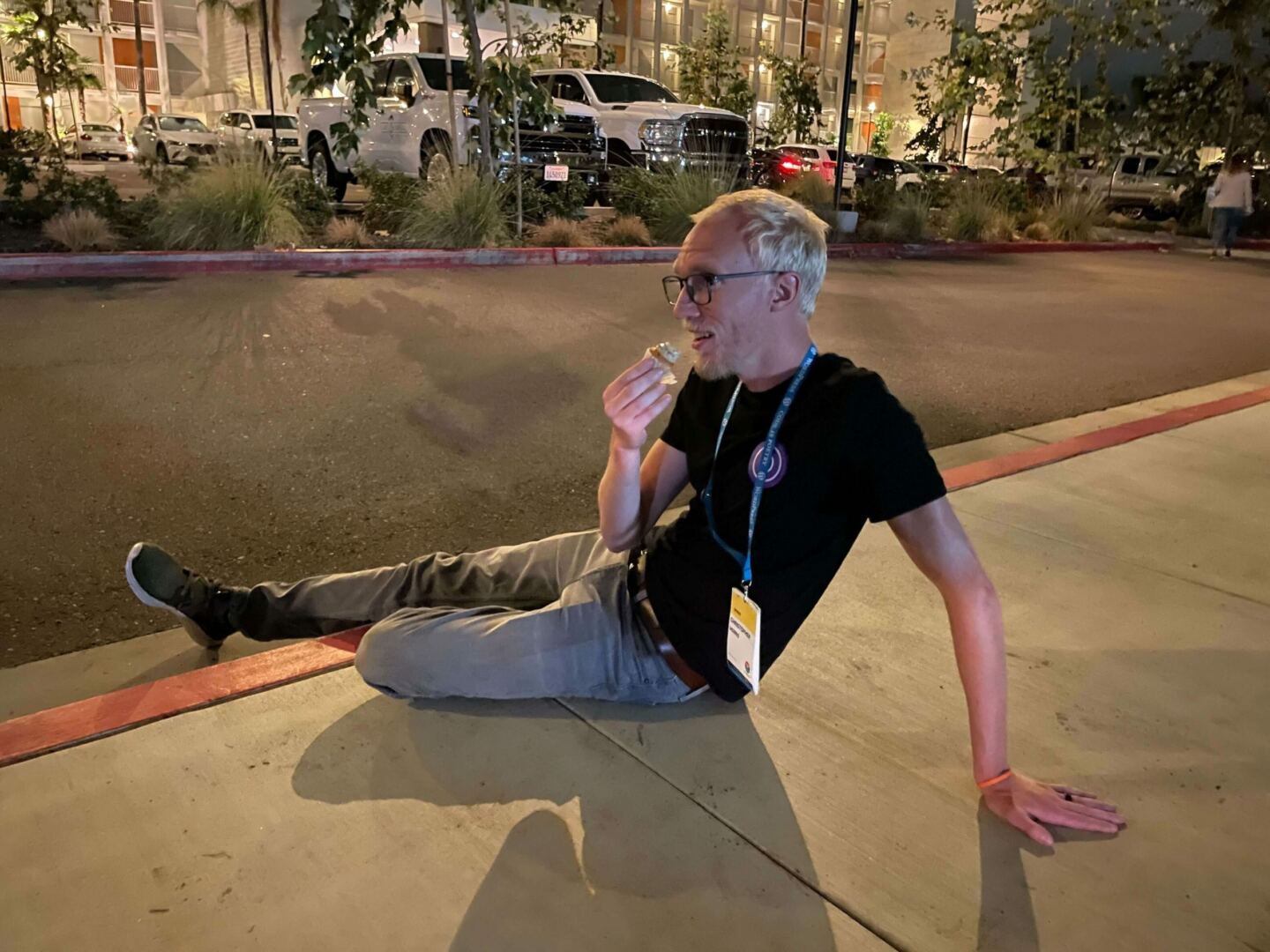 Chris sitting on a sidewalk curb at night