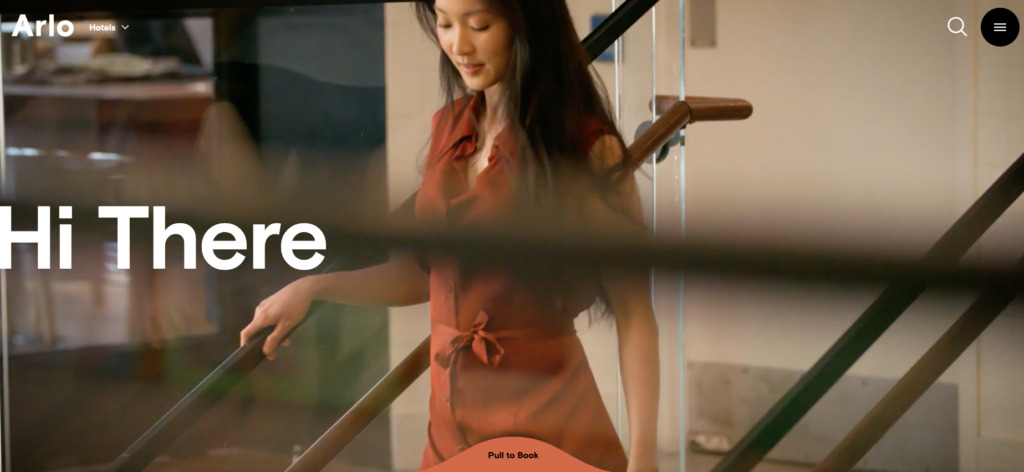 A screenshot of the arlo hotel website, a woman walks down the stairs